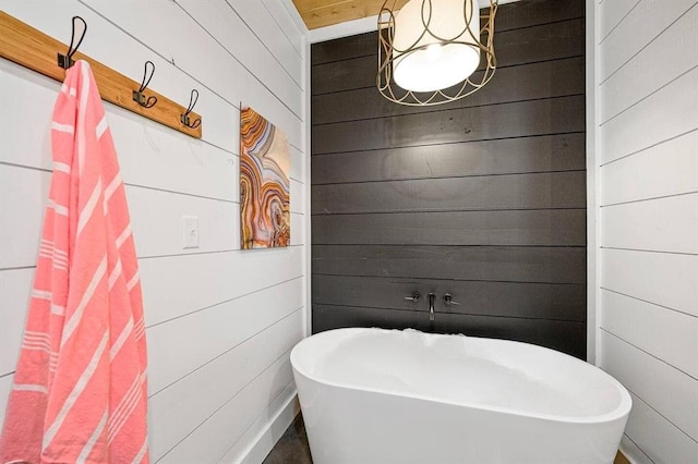 bathroom featuring a bathtub and wood walls