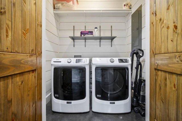 clothes washing area with washer and dryer and wood walls