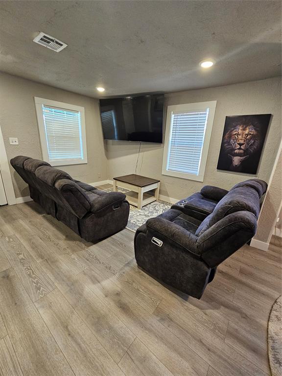 living room featuring a wealth of natural light, a textured ceiling, and light wood-type flooring