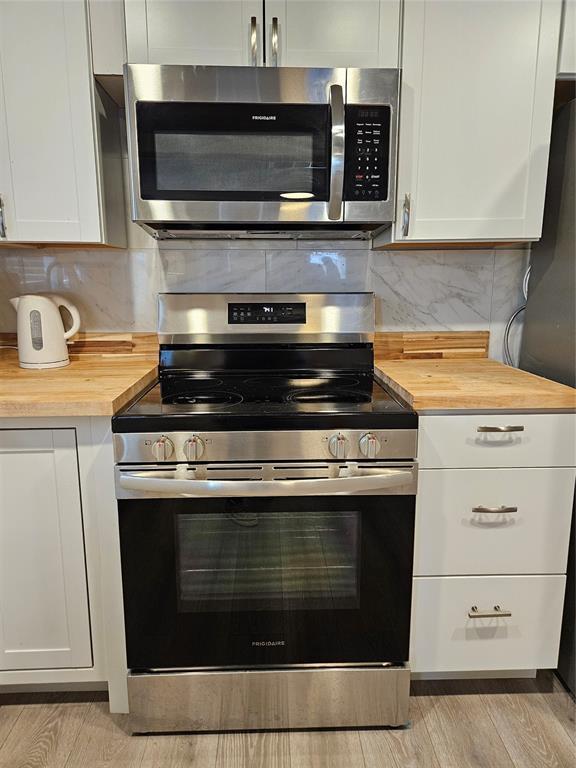 kitchen featuring backsplash, stainless steel appliances, butcher block counters, and white cabinets