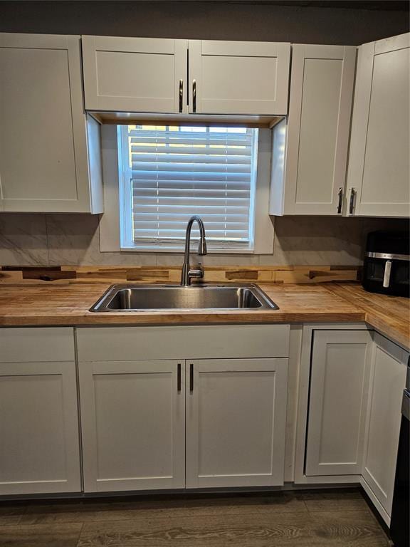 kitchen featuring dark hardwood / wood-style flooring, sink, white cabinets, and butcher block countertops