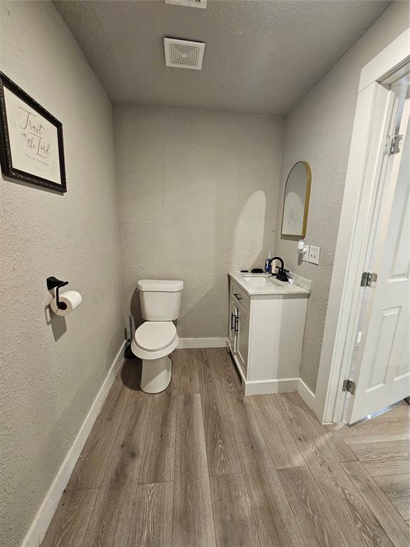 bathroom with vanity, a textured ceiling, wood-type flooring, and toilet