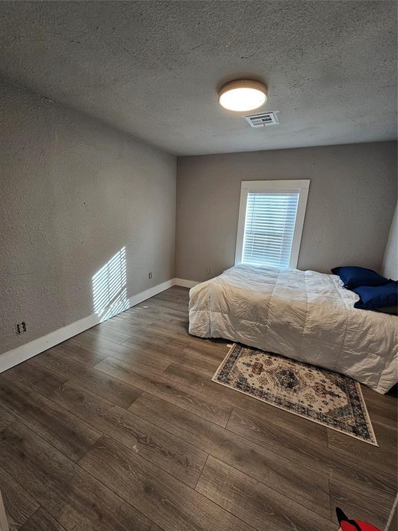 unfurnished bedroom featuring dark wood-type flooring and a textured ceiling