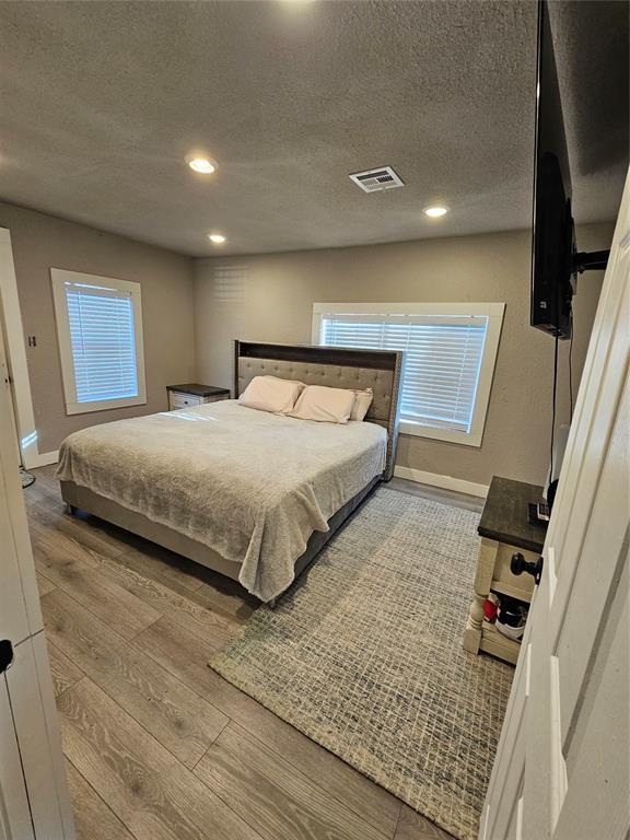 bedroom featuring a textured ceiling and light hardwood / wood-style floors