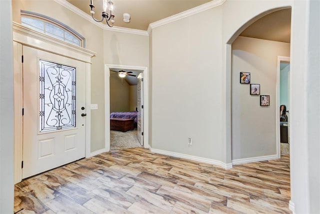 foyer entrance with crown molding, ceiling fan with notable chandelier, and light wood-type flooring