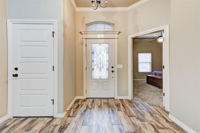 foyer entrance featuring an inviting chandelier, ornamental molding, and light wood-type flooring