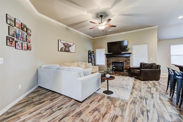 living room with ornamental molding, a stone fireplace, and wood-type flooring