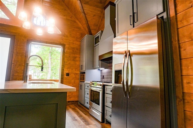 kitchen featuring wooden walls, lofted ceiling, sink, wood ceiling, and stainless steel appliances