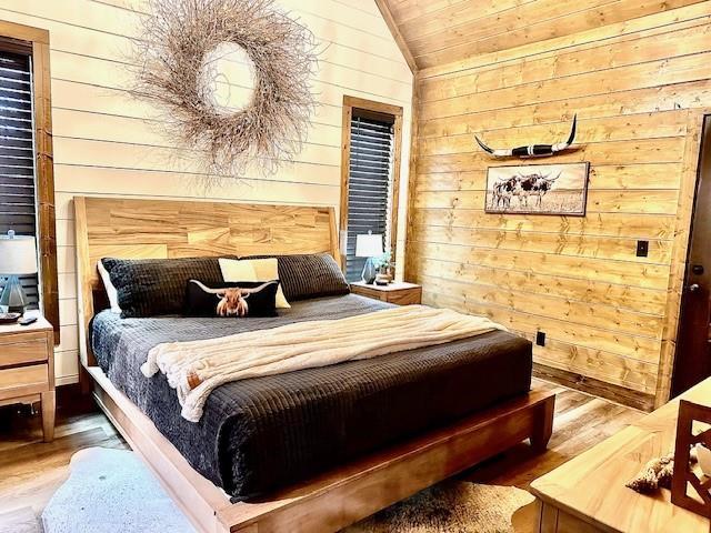 bedroom featuring lofted ceiling, wood-type flooring, wooden ceiling, and wood walls