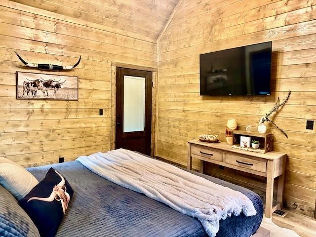 bedroom featuring vaulted ceiling and wooden walls