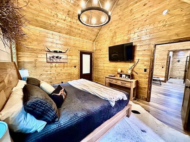 bedroom featuring hardwood / wood-style floors, high vaulted ceiling, and wood walls