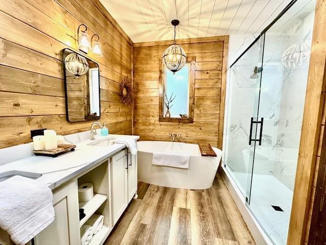 bathroom featuring vanity, hardwood / wood-style flooring, wooden walls, and separate shower and tub