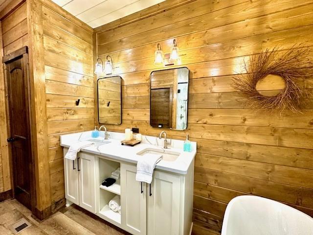 bathroom with vanity, a bathtub, and wooden walls