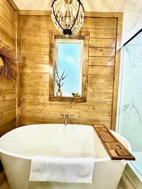 bathroom featuring an inviting chandelier, wooden walls, a bathing tub, and wooden ceiling