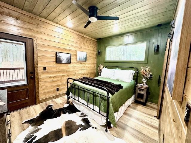 bedroom featuring ceiling fan, wooden walls, wood ceiling, and light wood-type flooring