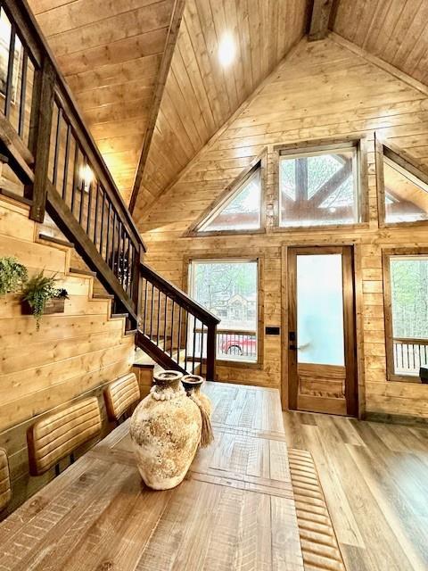 entrance foyer featuring wood ceiling, high vaulted ceiling, wood walls, beamed ceiling, and light wood-type flooring