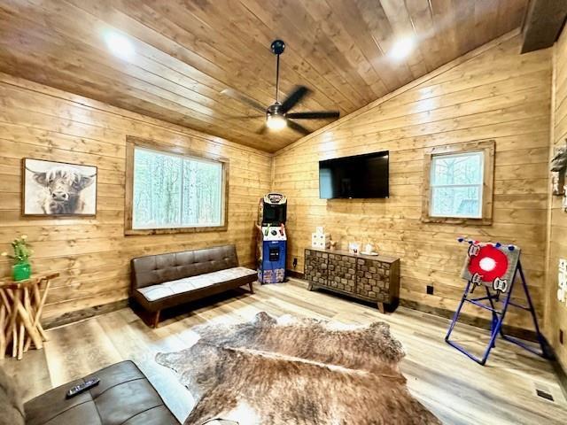 living room featuring lofted ceiling, wood ceiling, light hardwood / wood-style flooring, wooden walls, and ceiling fan