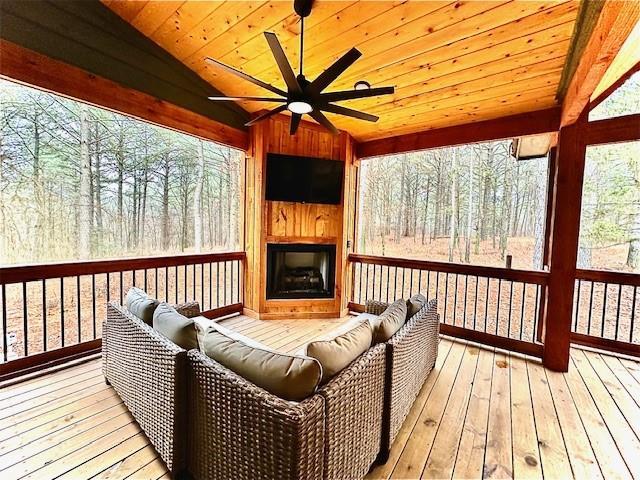 wooden deck featuring ceiling fan and a large fireplace