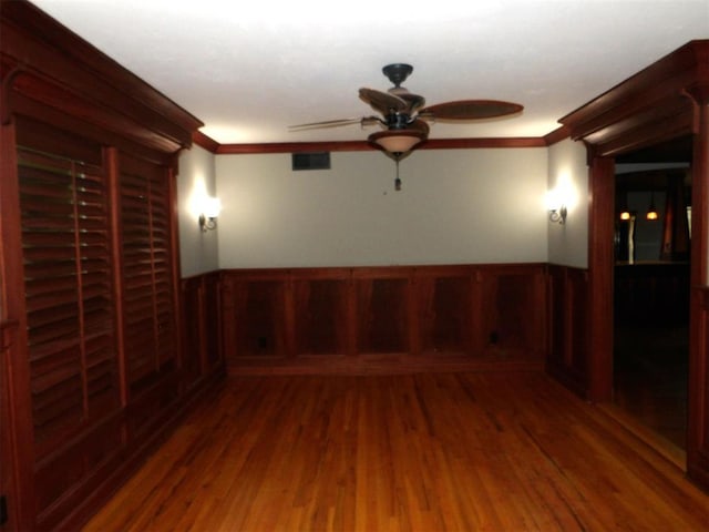 spare room with crown molding, ceiling fan, hardwood / wood-style floors, and wood walls