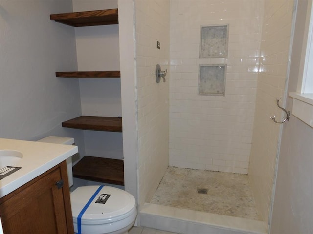 bathroom featuring vanity, tiled shower, and toilet