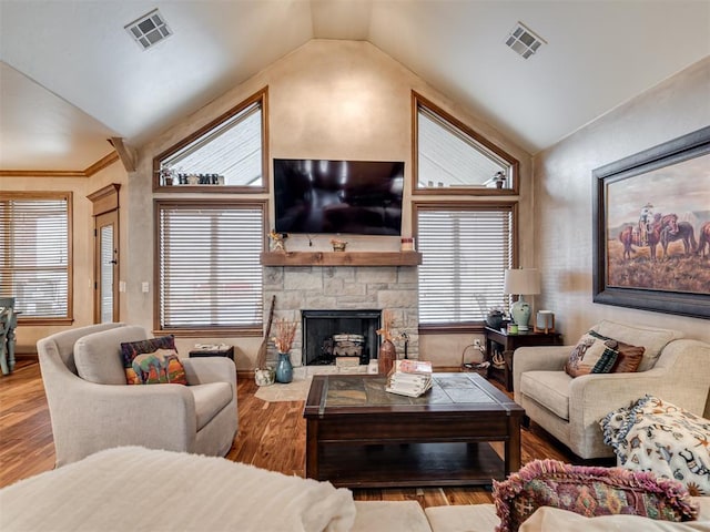 living room featuring hardwood / wood-style flooring, lofted ceiling, and a stone fireplace