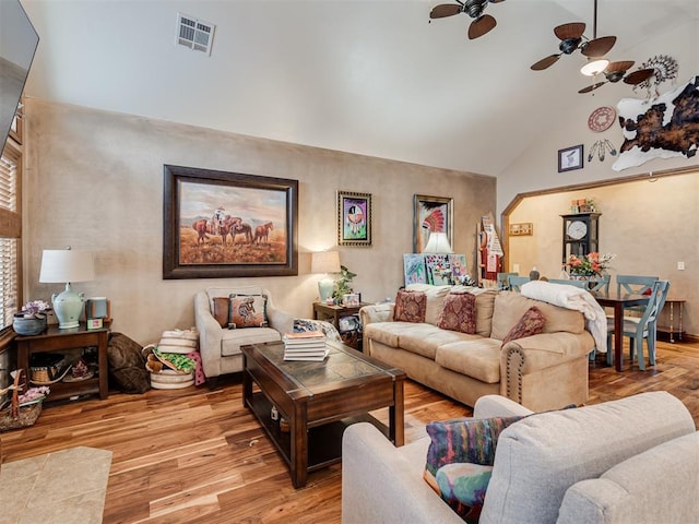 living area with lofted ceiling, visible vents, ceiling fan, and light wood-style flooring