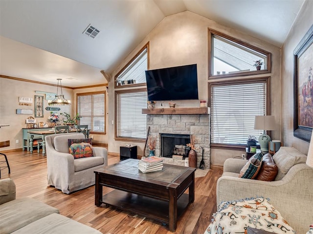 living room featuring vaulted ceiling, a stone fireplace, and hardwood / wood-style floors