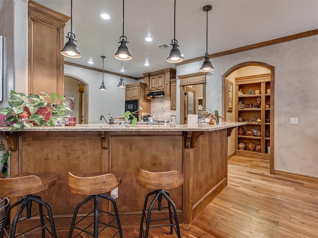 kitchen with arched walkways, black microwave, a breakfast bar, visible vents, and pendant lighting