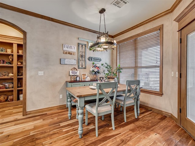 dining area featuring light wood-type flooring, baseboards, visible vents, and ornamental molding