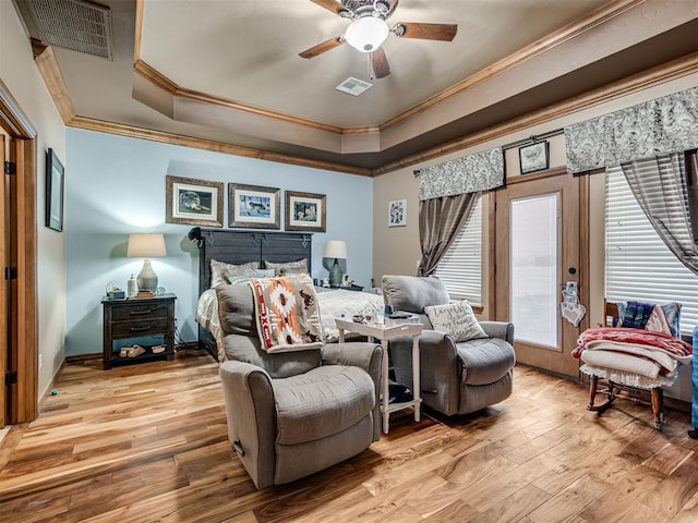 bedroom with ceiling fan, ornamental molding, a raised ceiling, and light hardwood / wood-style flooring