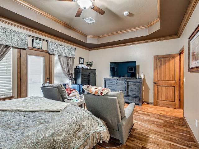 bedroom featuring a tray ceiling, wood-type flooring, ornamental molding, and ceiling fan