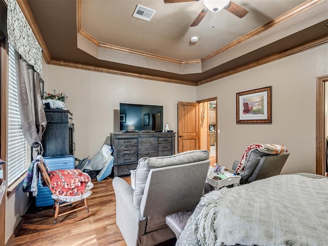 bedroom with ceiling fan, ornamental molding, a tray ceiling, and hardwood / wood-style floors