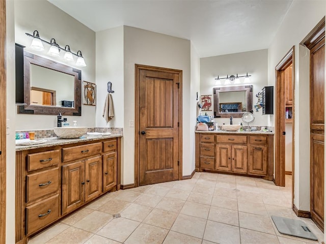 bathroom featuring tile patterned flooring, two vanities, a sink, and baseboards