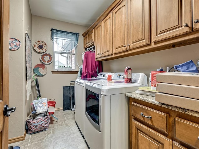 clothes washing area with light tile patterned floors, washer and clothes dryer, and cabinets