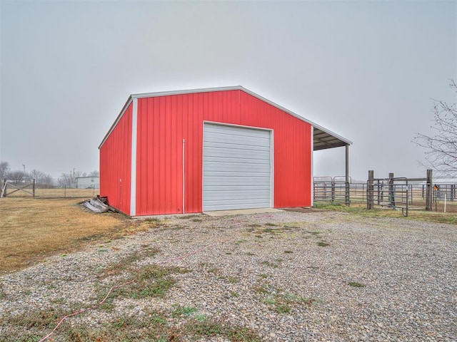 view of outdoor structure featuring driveway, fence, and an outdoor structure