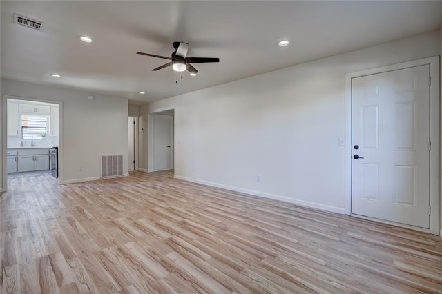 empty room with sink, ceiling fan, and light hardwood / wood-style flooring