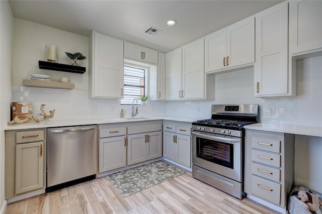 kitchen featuring sink, light hardwood / wood-style flooring, gray cabinets, appliances with stainless steel finishes, and decorative backsplash