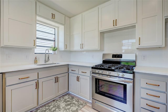 kitchen featuring tasteful backsplash, gas range, sink, and white cabinets