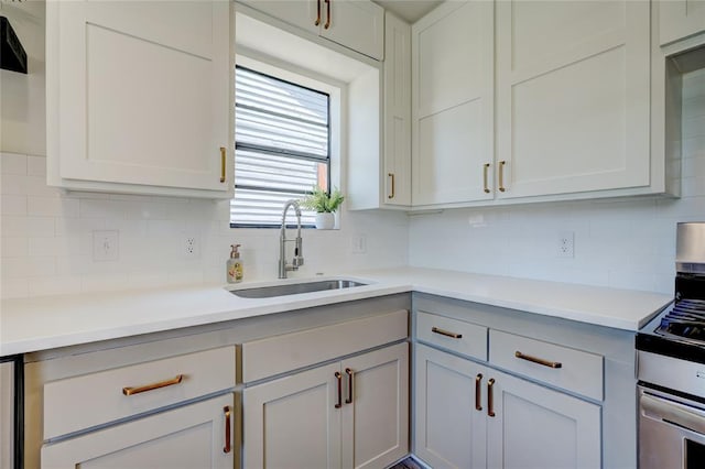 kitchen featuring tasteful backsplash, sink, stainless steel range with gas stovetop, and white cabinets