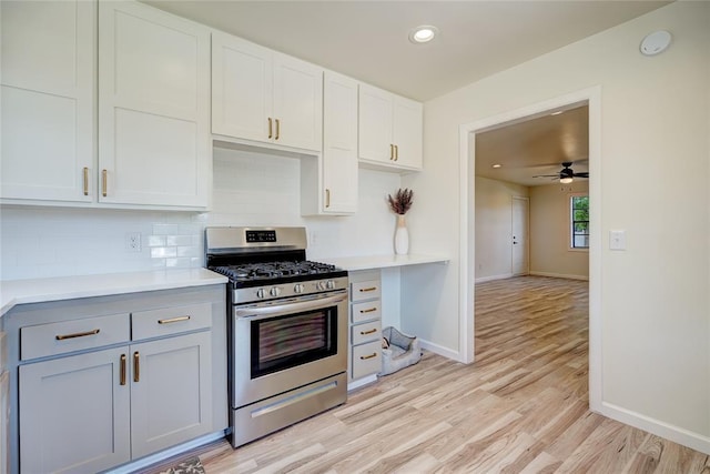 kitchen featuring gas range, tasteful backsplash, light hardwood / wood-style flooring, ceiling fan, and white cabinets