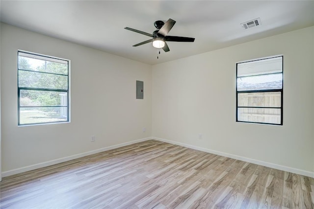 empty room featuring plenty of natural light, electric panel, ceiling fan, and light hardwood / wood-style flooring