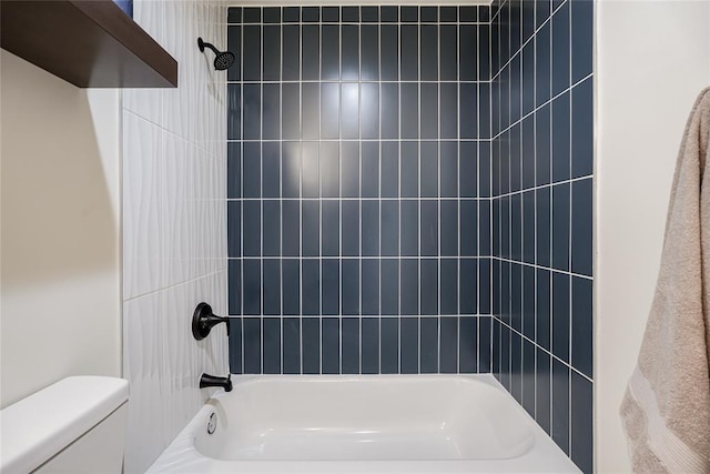 bathroom featuring toilet and tiled shower / bath