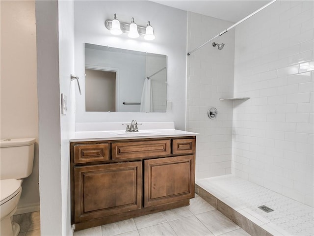 bathroom with vanity, a tile shower, tile patterned floors, and toilet