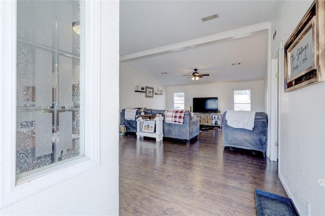 living room featuring ceiling fan, dark hardwood / wood-style floors, and vaulted ceiling with beams