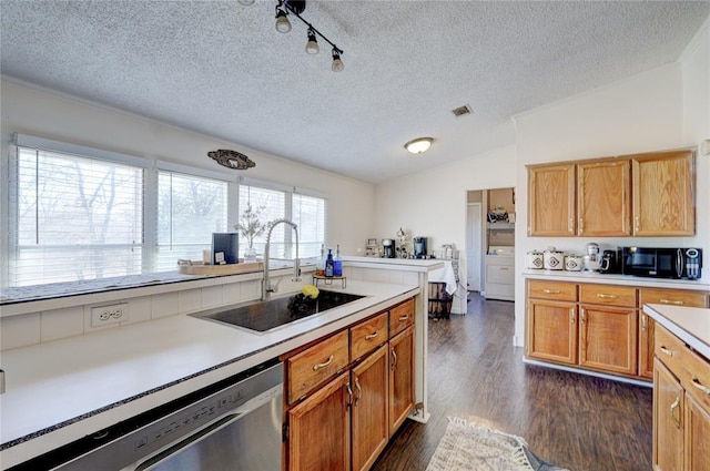 kitchen with sink, dark wood-type flooring, dishwasher, washer / dryer, and vaulted ceiling