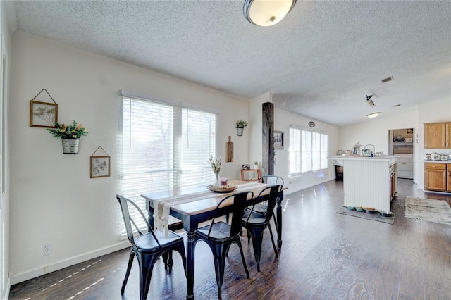 dining room with dark wood-type flooring, vaulted ceiling, and a textured ceiling