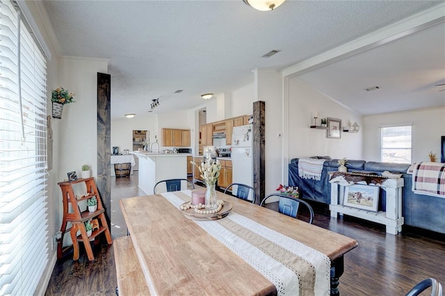 dining area with vaulted ceiling with beams, crown molding, dark wood-type flooring, and a textured ceiling