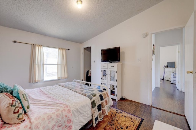 bedroom with lofted ceiling, dark wood-type flooring, and a textured ceiling