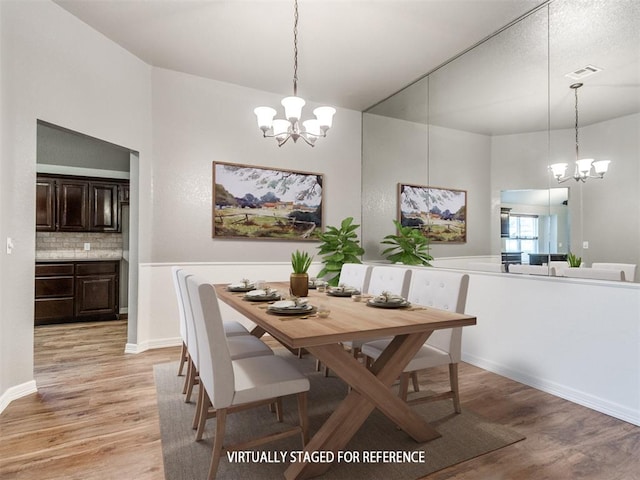 dining area with light hardwood / wood-style flooring and a notable chandelier