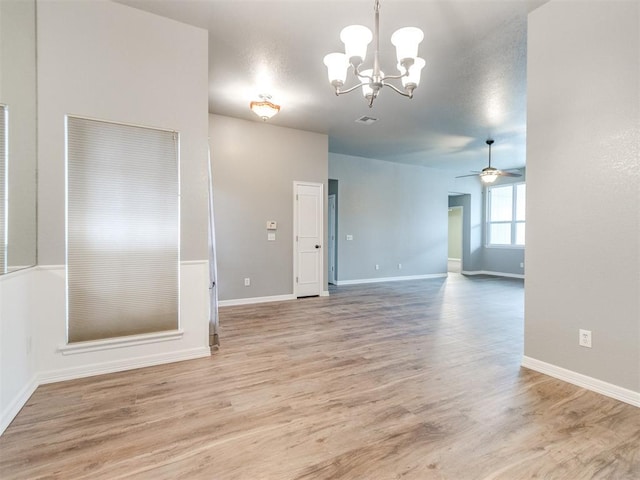 empty room featuring ceiling fan with notable chandelier and light wood-type flooring